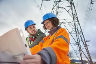 Electricity engineers beneath a pylon